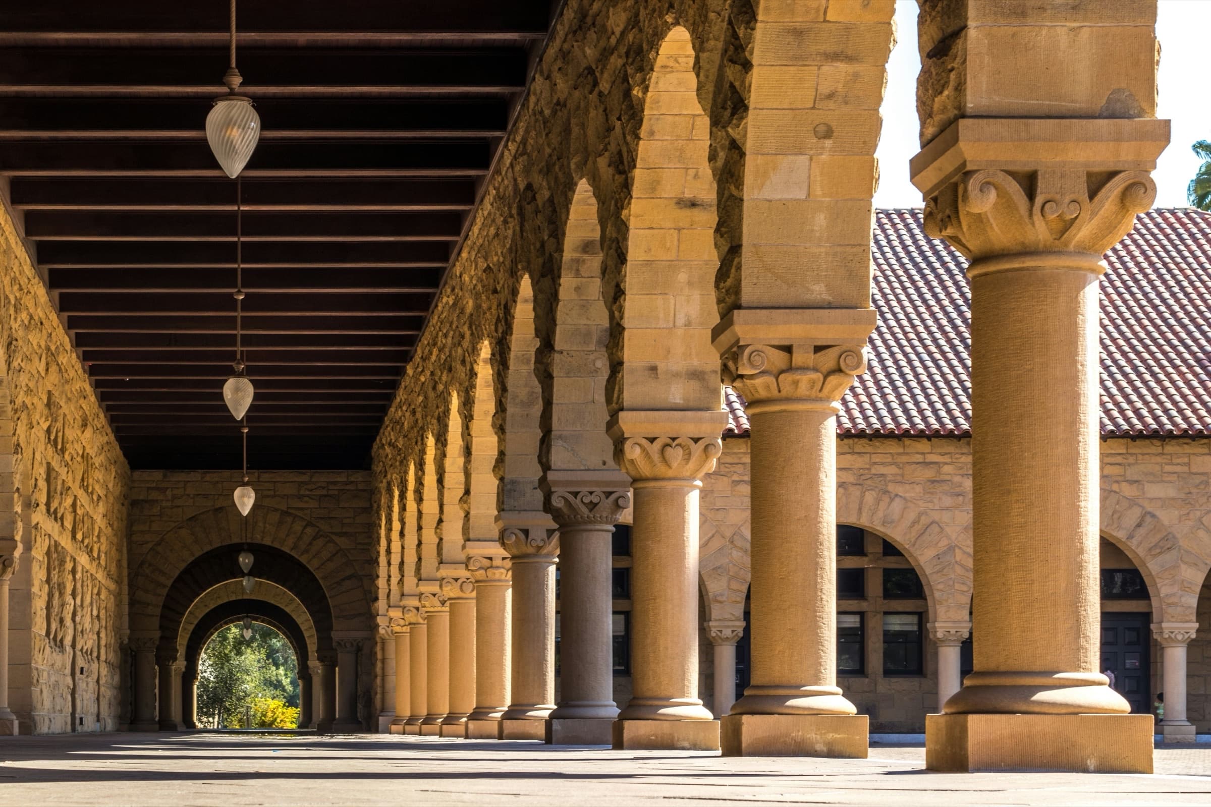 Sunlit colonnade with sandstone arches receding into the distance