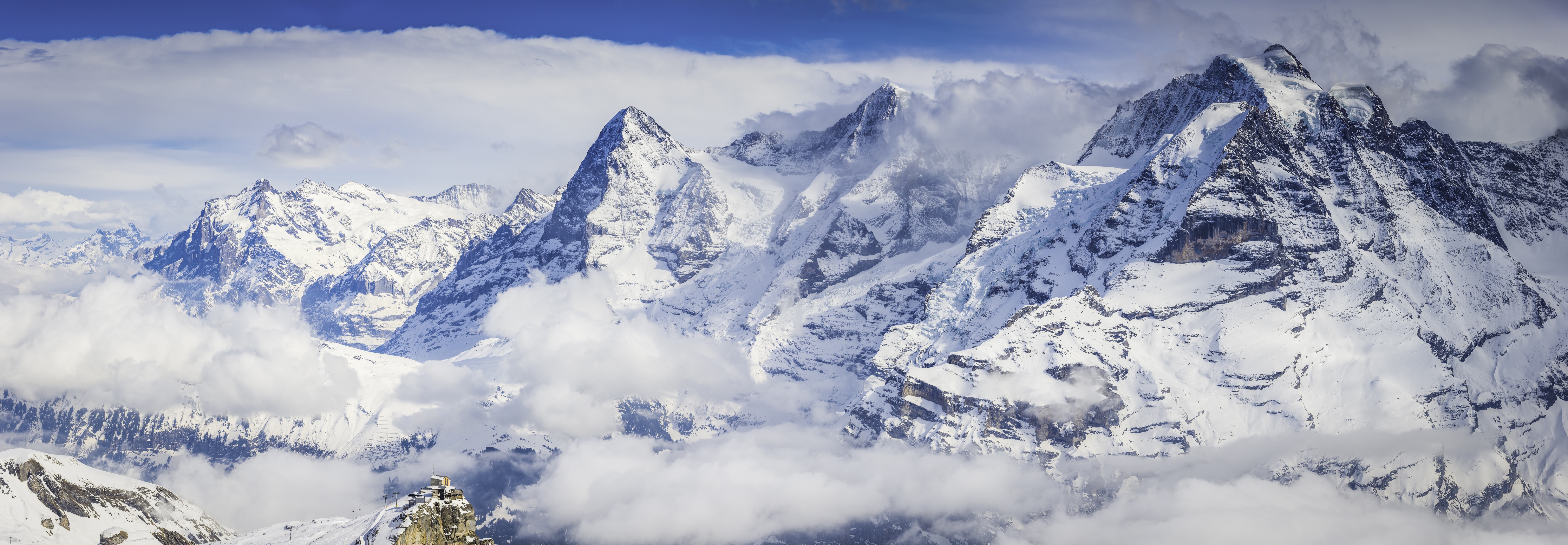 Snowy Eiger, Mönch and Jungfrau peaks amid dramatic cloud above a sea of mist